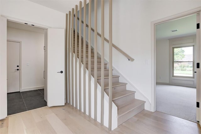 stairway with wood finished floors and visible vents