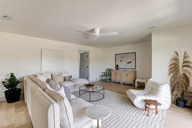 living area featuring light wood-type flooring, baseboards, visible vents, and ceiling fan