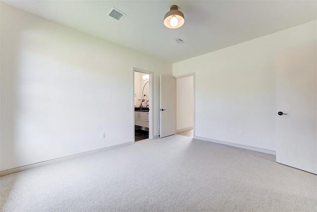 unfurnished bedroom with light colored carpet, visible vents, ensuite bathroom, and baseboards