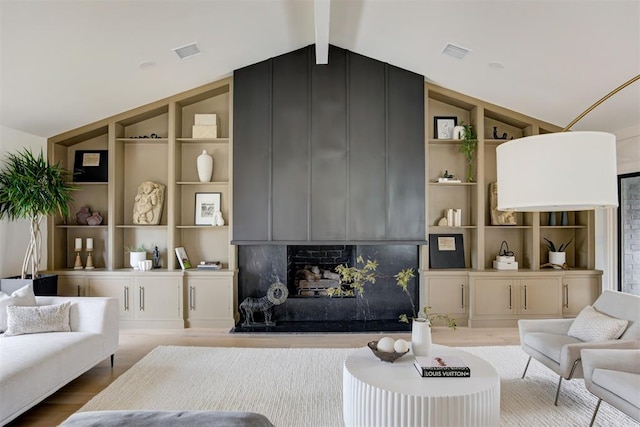 living room featuring hardwood / wood-style floors, built in shelves, lofted ceiling with beams, and a fireplace