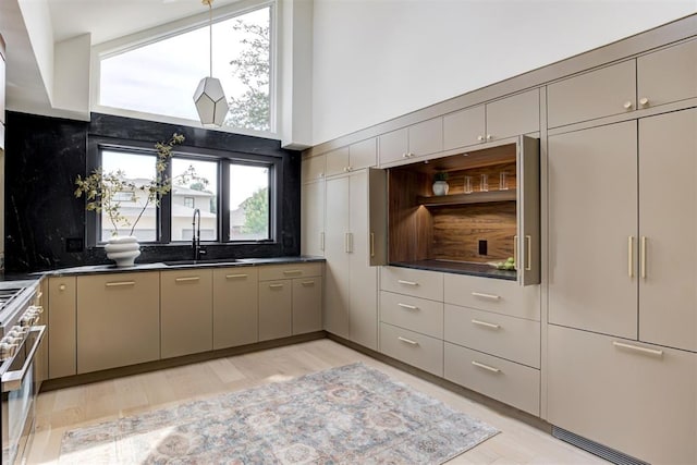 kitchen featuring a sink, a towering ceiling, high end stainless steel range, dark countertops, and backsplash