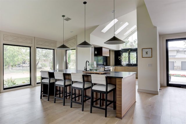 kitchen with dark countertops, visible vents, light wood-style flooring, and pendant lighting