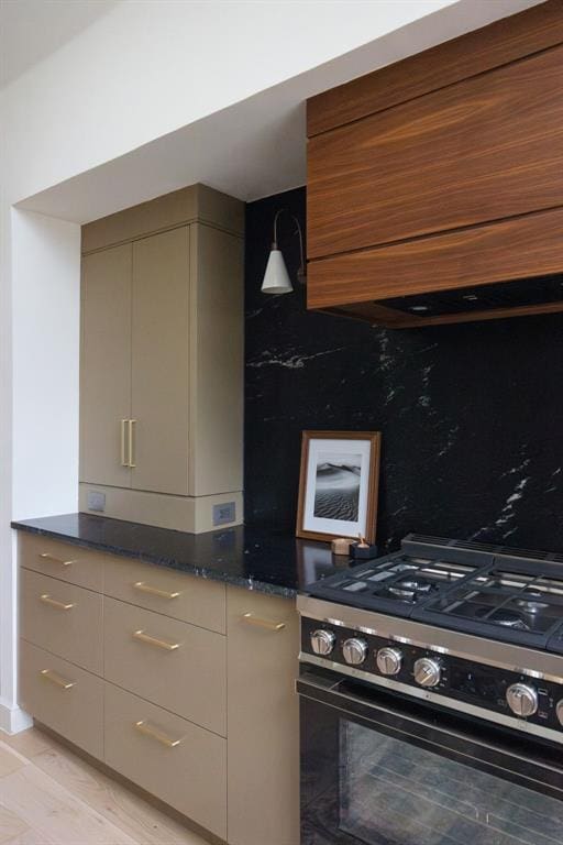 kitchen featuring gas stove, decorative backsplash, modern cabinets, and dark stone counters