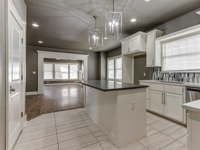 kitchen with white cabinets, decorative light fixtures, light tile patterned floors, and sink