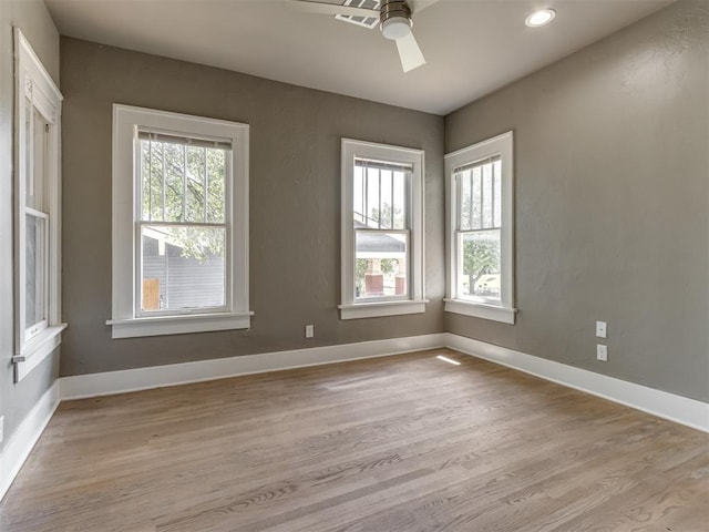 spare room with a wealth of natural light, ceiling fan, and light hardwood / wood-style floors