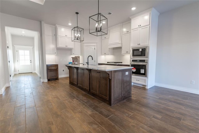 kitchen with stainless steel oven, dark wood-type flooring, an island with sink, a breakfast bar, and built in microwave