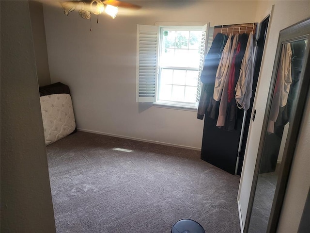 unfurnished bedroom with ceiling fan and dark carpet