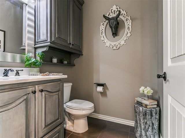 bathroom with toilet, vanity, and tile patterned floors