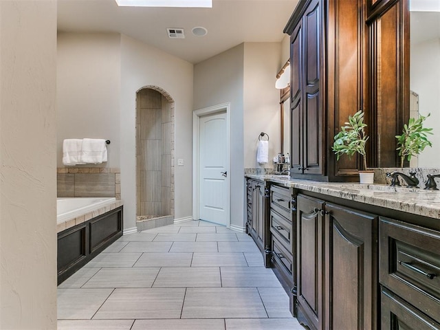 bathroom with a tub to relax in, vanity, and a skylight