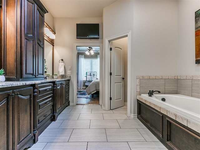 bathroom featuring tile patterned floors, vanity, ceiling fan, and tiled tub