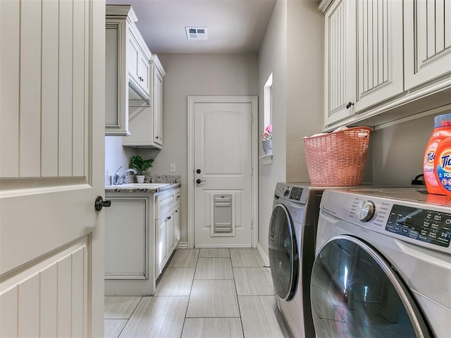 washroom featuring cabinets, independent washer and dryer, and sink