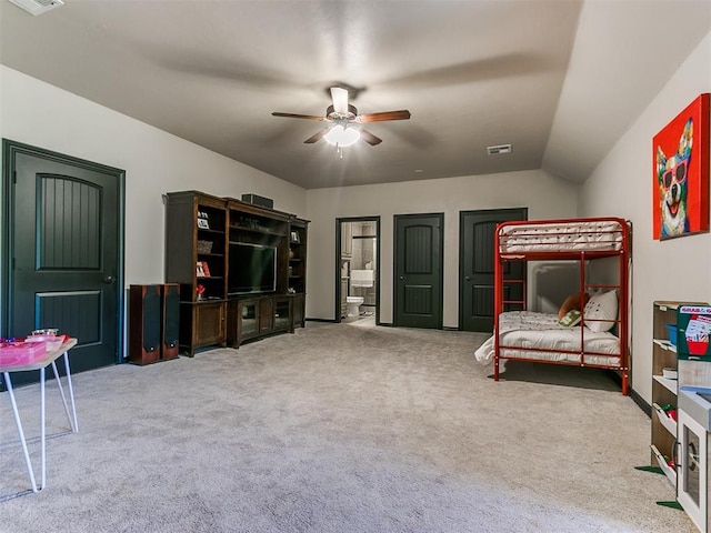 carpeted bedroom with ceiling fan, lofted ceiling, and ensuite bath