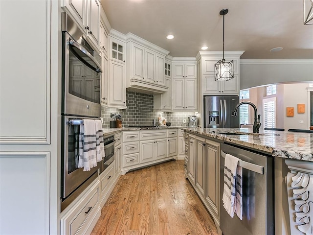 kitchen featuring backsplash, white cabinets, ornamental molding, decorative light fixtures, and light stone counters