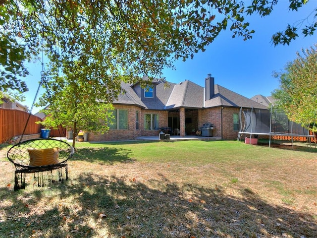 back of property featuring a lawn, a trampoline, and a patio