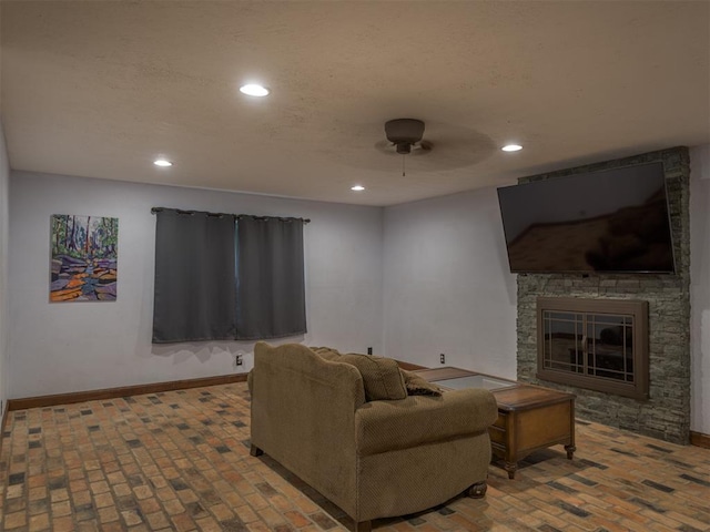 living room with ceiling fan and a stone fireplace