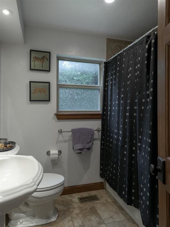 bathroom featuring toilet and curtained shower