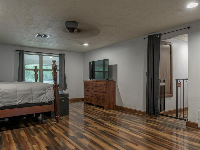 bedroom featuring dark hardwood / wood-style flooring, a textured ceiling, and ceiling fan