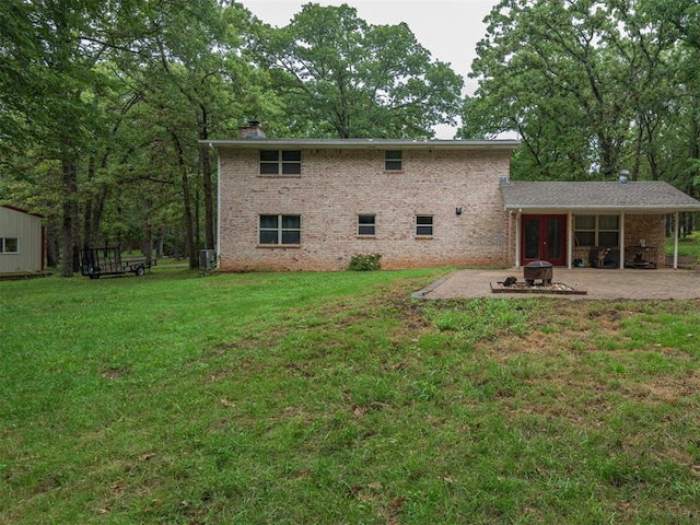 rear view of house featuring a yard, a patio, and an outdoor fire pit