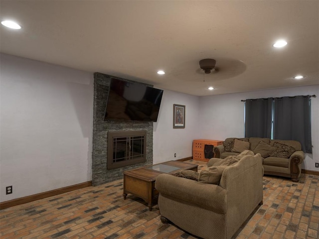 living room featuring a stone fireplace and ceiling fan