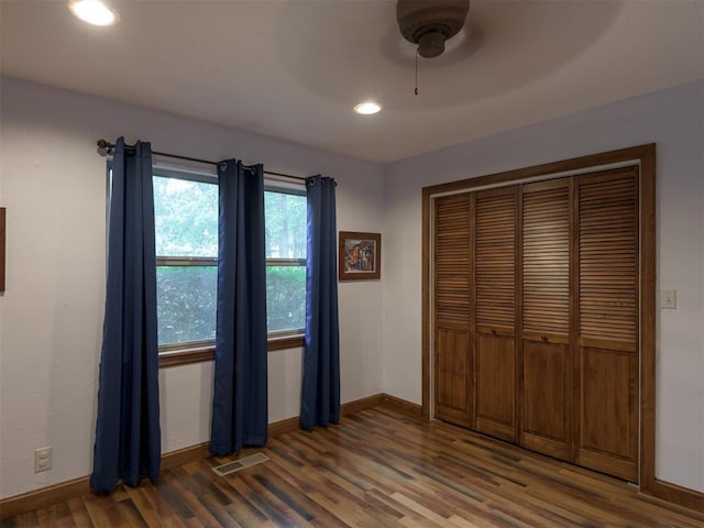 unfurnished bedroom with dark wood-type flooring, a closet, and ceiling fan