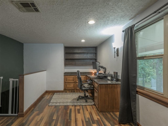 office space featuring dark wood-type flooring, built in desk, and a textured ceiling