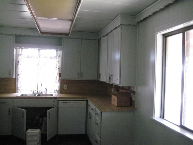 kitchen featuring backsplash, white dishwasher, sink, and white cabinets