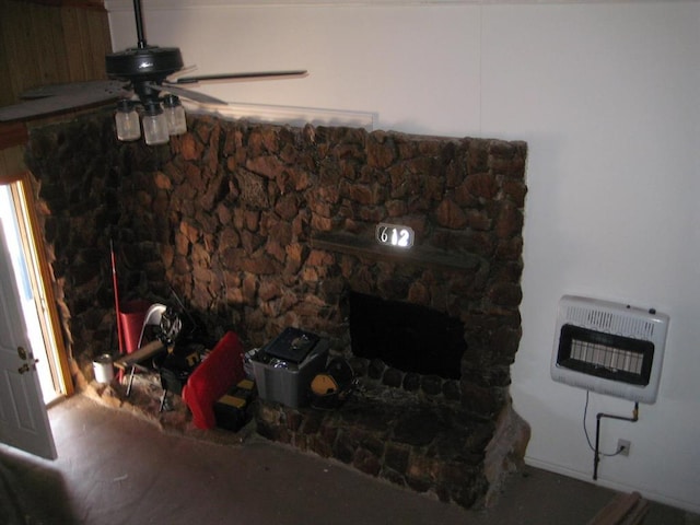 living room with ceiling fan, a stone fireplace, and heating unit