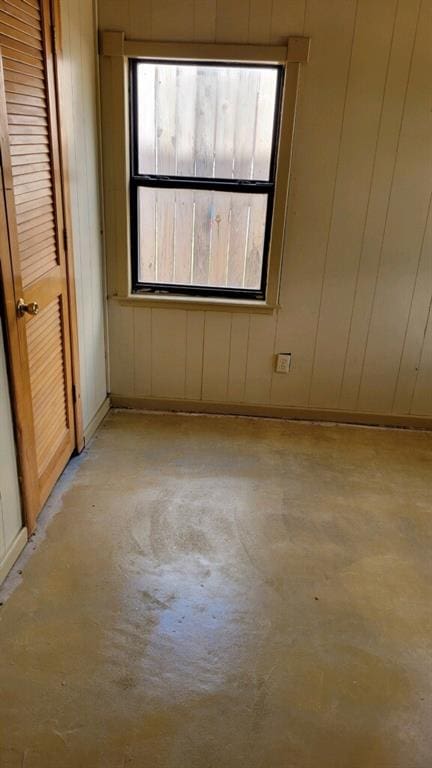 empty room featuring a healthy amount of sunlight and wood walls