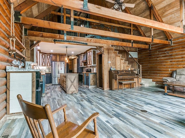 unfurnished living room featuring ceiling fan, log walls, high vaulted ceiling, beamed ceiling, and light wood-type flooring