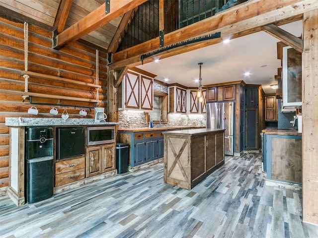 kitchen with backsplash, a center island, stainless steel appliances, vaulted ceiling with beams, and light hardwood / wood-style floors