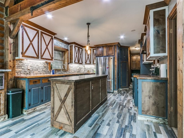 kitchen featuring stainless steel fridge, light wood-type flooring, decorative light fixtures, a center island, and butcher block countertops