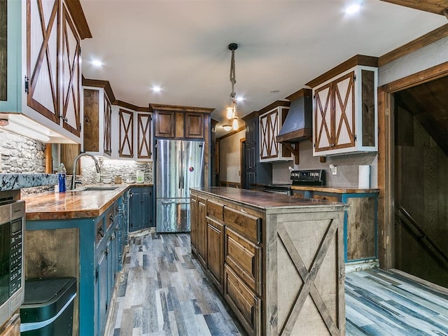 kitchen featuring wood counters, appliances with stainless steel finishes, premium range hood, sink, and light hardwood / wood-style floors