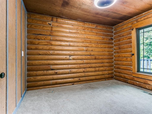 carpeted empty room with wooden ceiling and rustic walls