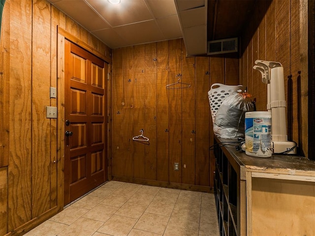 foyer entrance with wooden walls and light tile patterned flooring