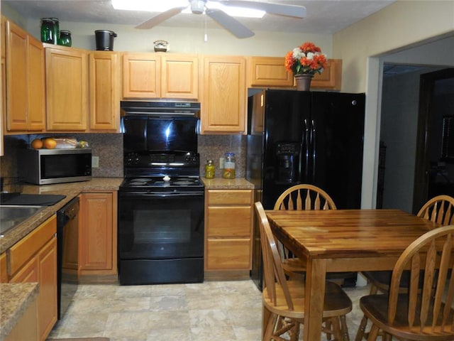 kitchen with light stone countertops, decorative backsplash, black appliances, and range hood