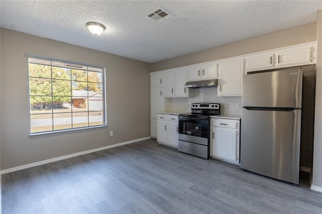 kitchen featuring white cabinets, backsplash, stainless steel appliances, and hardwood / wood-style floors