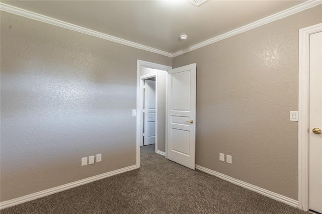 empty room with ornamental molding and dark colored carpet