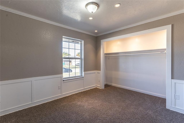 unfurnished bedroom with dark carpet, ornamental molding, a textured ceiling, and a closet