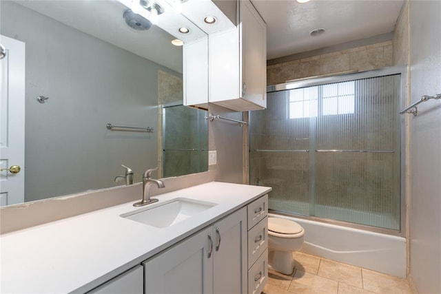 full bathroom with tile patterned floors, combined bath / shower with glass door, toilet, and vanity