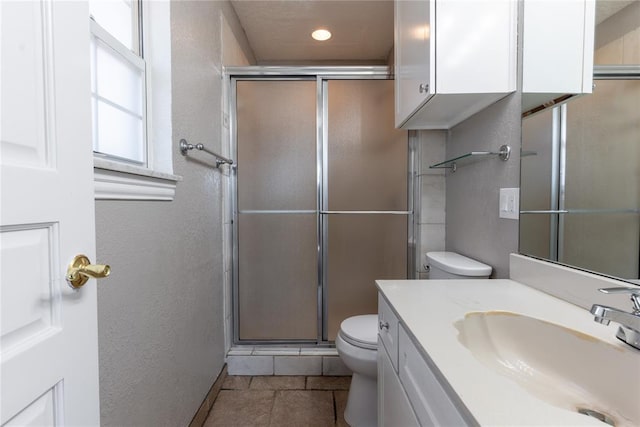 bathroom with tile patterned flooring, vanity, toilet, and a shower with shower door