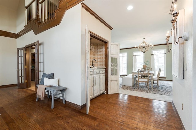 hallway featuring ornamental molding, dark hardwood / wood-style flooring, and a notable chandelier