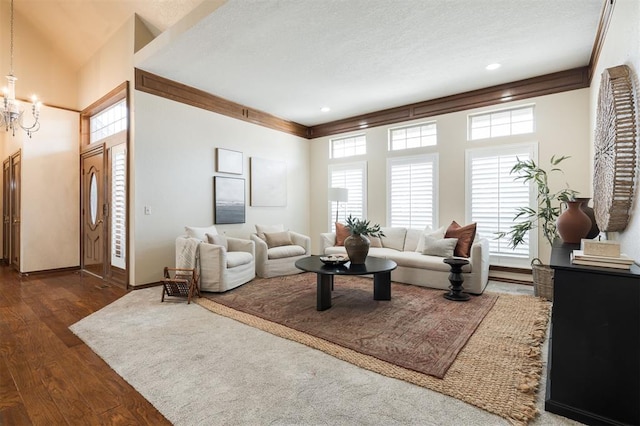 living room with an inviting chandelier, dark hardwood / wood-style floors, and ornamental molding