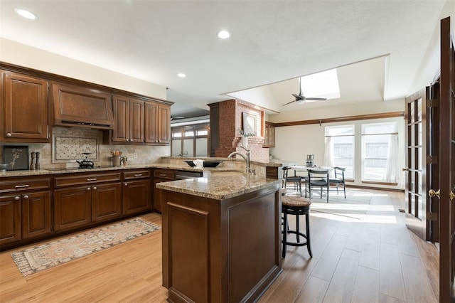 kitchen with a kitchen breakfast bar, light wood-type flooring, plenty of natural light, and tasteful backsplash