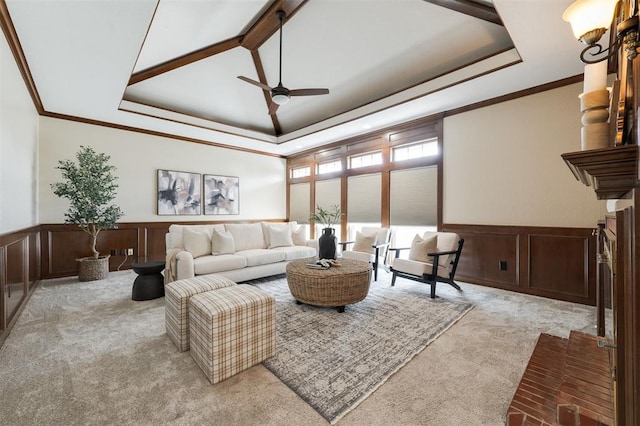 carpeted living room with ceiling fan, a raised ceiling, and ornamental molding