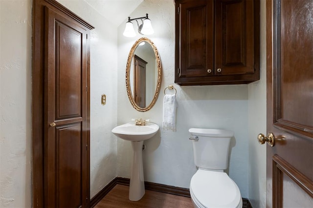 bathroom with hardwood / wood-style floors, vaulted ceiling, and toilet