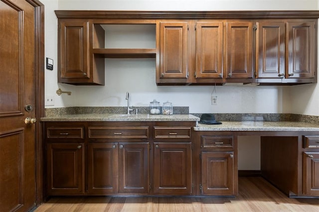 kitchen with stone counters, sink, and light hardwood / wood-style floors