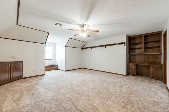 bonus room featuring a textured ceiling, light colored carpet, and ceiling fan