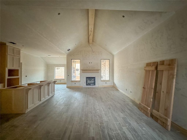 unfurnished living room featuring vaulted ceiling with beams and hardwood / wood-style flooring