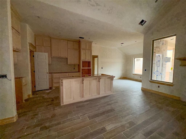 kitchen with hardwood / wood-style floors, a kitchen island, lofted ceiling, and light brown cabinets