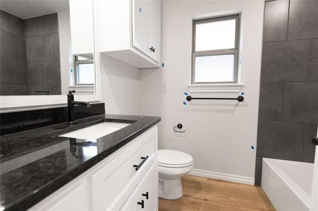 full bathroom featuring baseboards, toilet, wood finished floors, a bathtub, and vanity